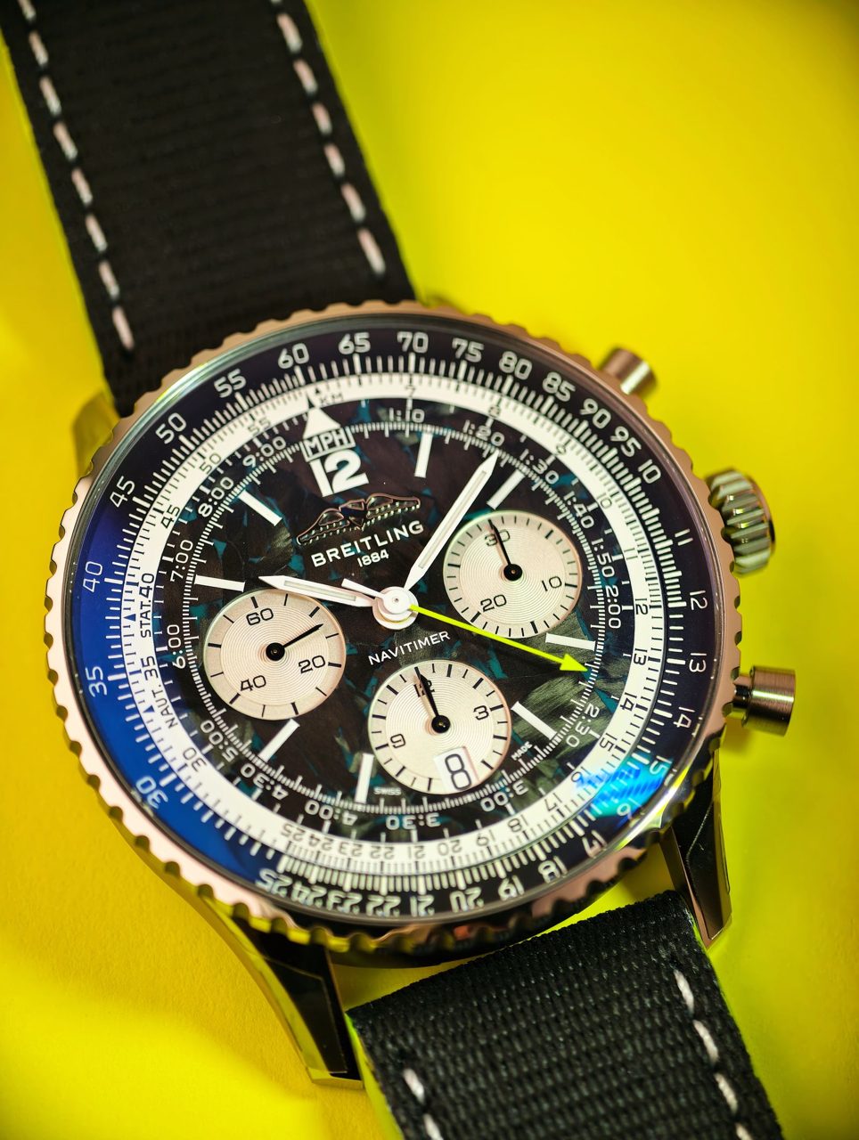 Breitling Navitimer mit Rechenschieber-Lünette und hellen Totalisatoren vor gelbem Hintergrund