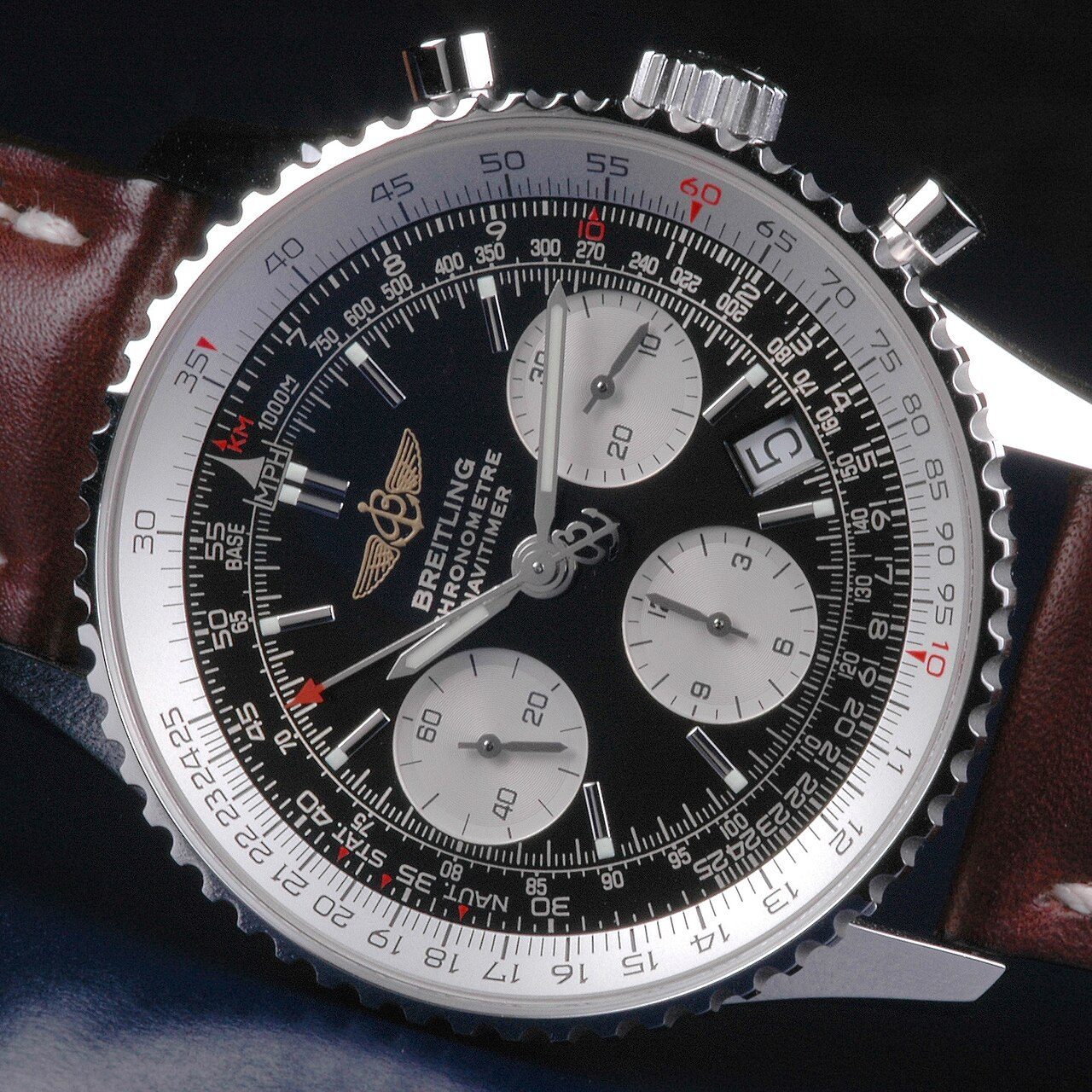 Nahaufnahme einer Breitling Navitimer mit schwarzem Zifferblatt, drei Hilfszifferblättern und den Skalen des Rechenschiebers auf der Lünette
