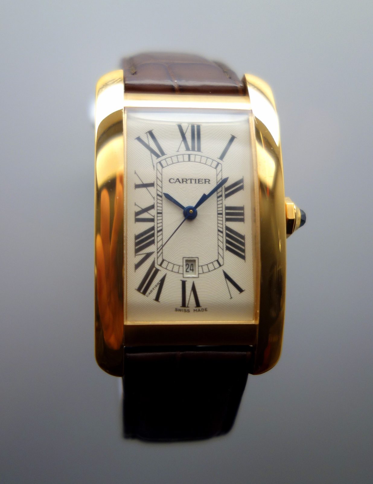 Hohe, leicht gewölbte Cartier Tank Américaine in Gelbgold mit braunem Lederband und dem Aufdruck «Swiss made» auf dem Zifferblatt