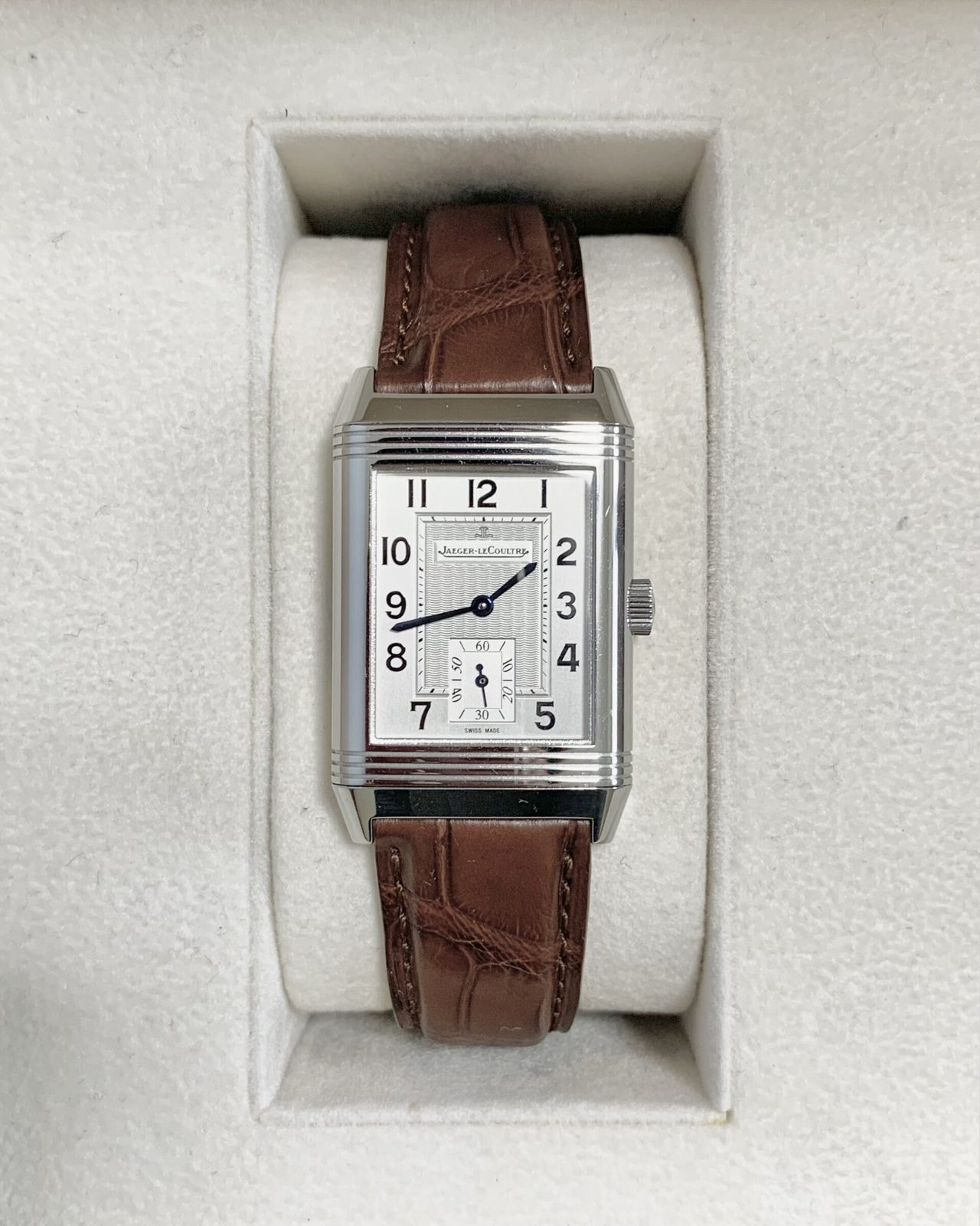 Jaeger-LeCoultre Reverso aus Stahl mit silbernem Zifferblatt, arabischen Ziffern und kleiner Sekunde an einem braunen Lederarmband in einer hellen Uhrenbox