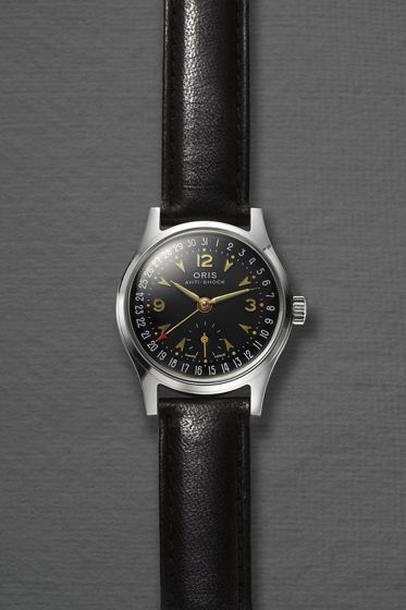 Armbanduhr von Oris mit schwarzem Zifferblatt, einem Datumsring am Rand und einem Zeiger mit rotem Pfeil, der das Datum anzeigt, an schwarzem Lederband