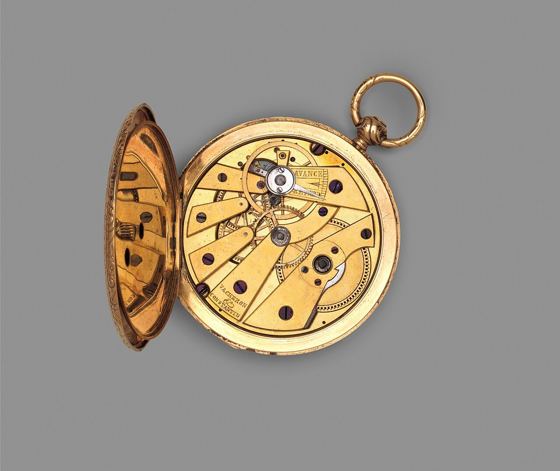 Geöffnete goldene Taschenuhr mit sichtbarem Messingwerk, das den Namenszug von Vacheron Constantin trägt, vor grauem Hintergrund