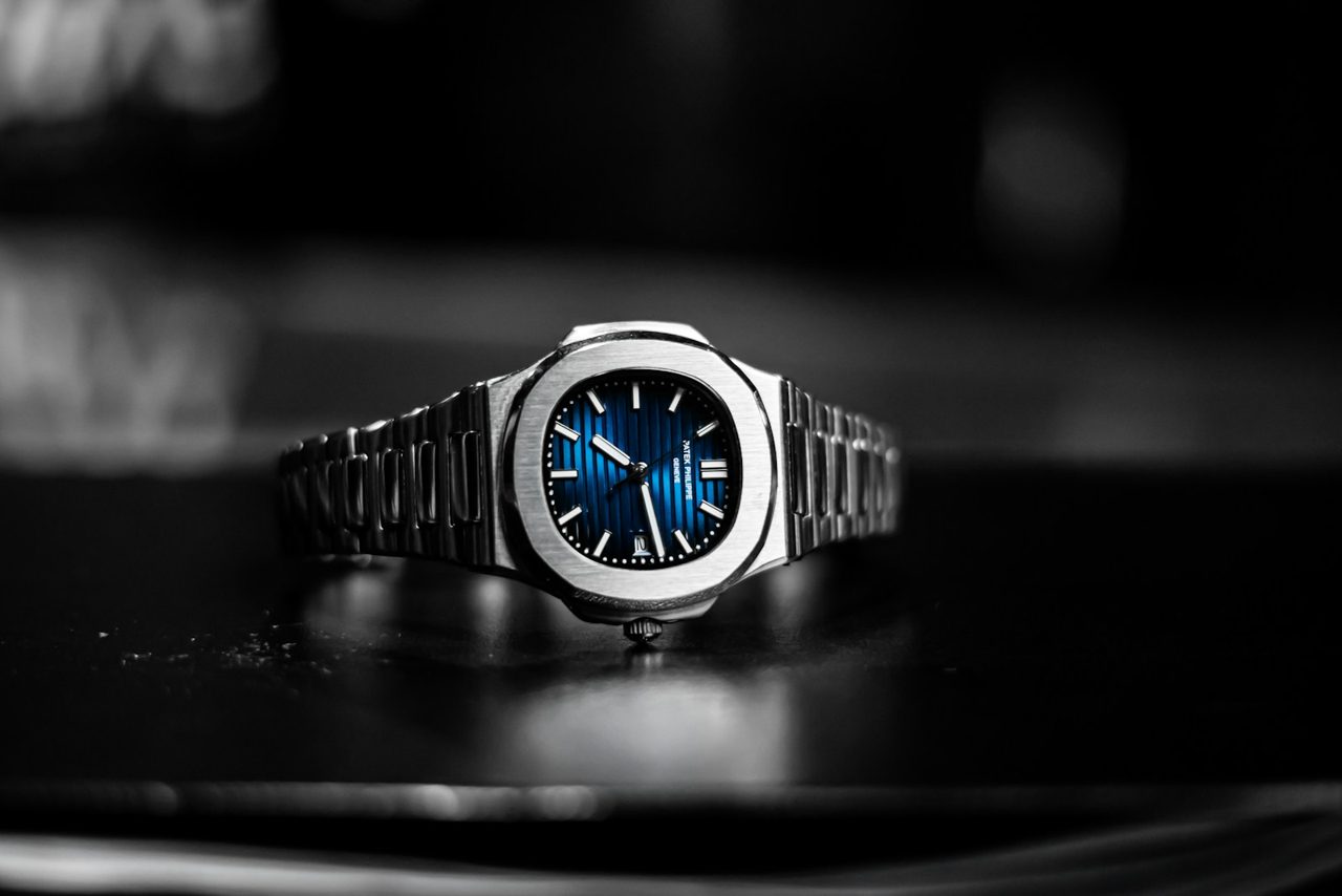 Patek Philippe Nautilus aus Stahl mit blau verlaufendem, horizontal gerilltem Zifferblatt vor schwarz-weissem Hintergrund