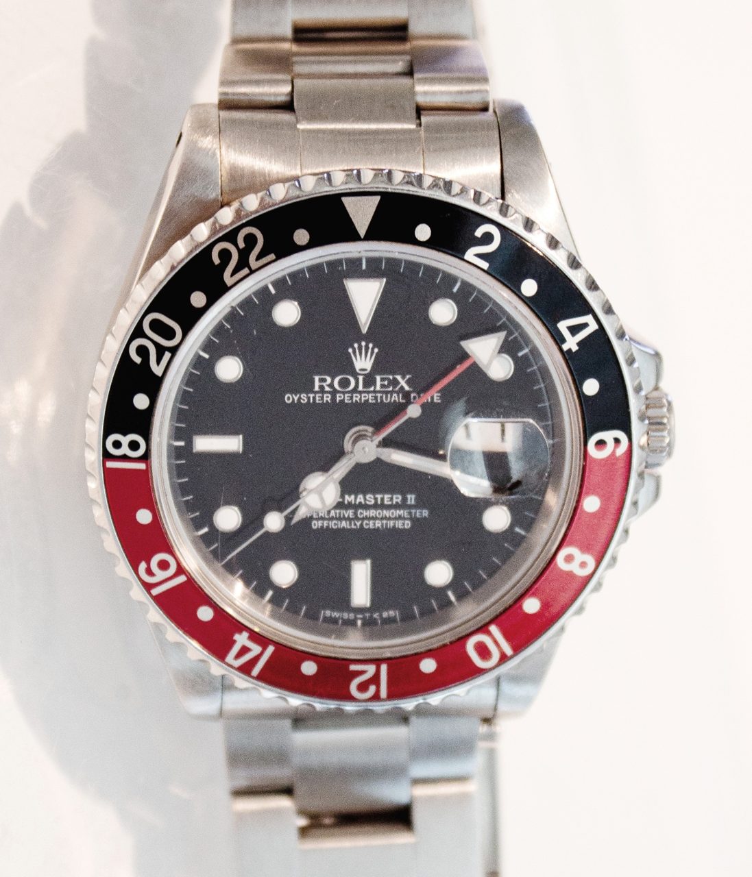 Stählerne Rolex GMT-Master II mit schwarzem Zifferblatt, rotem 24-Stunden-Zeiger und schwarz-roter Drehlünette, frontal fotografiert
