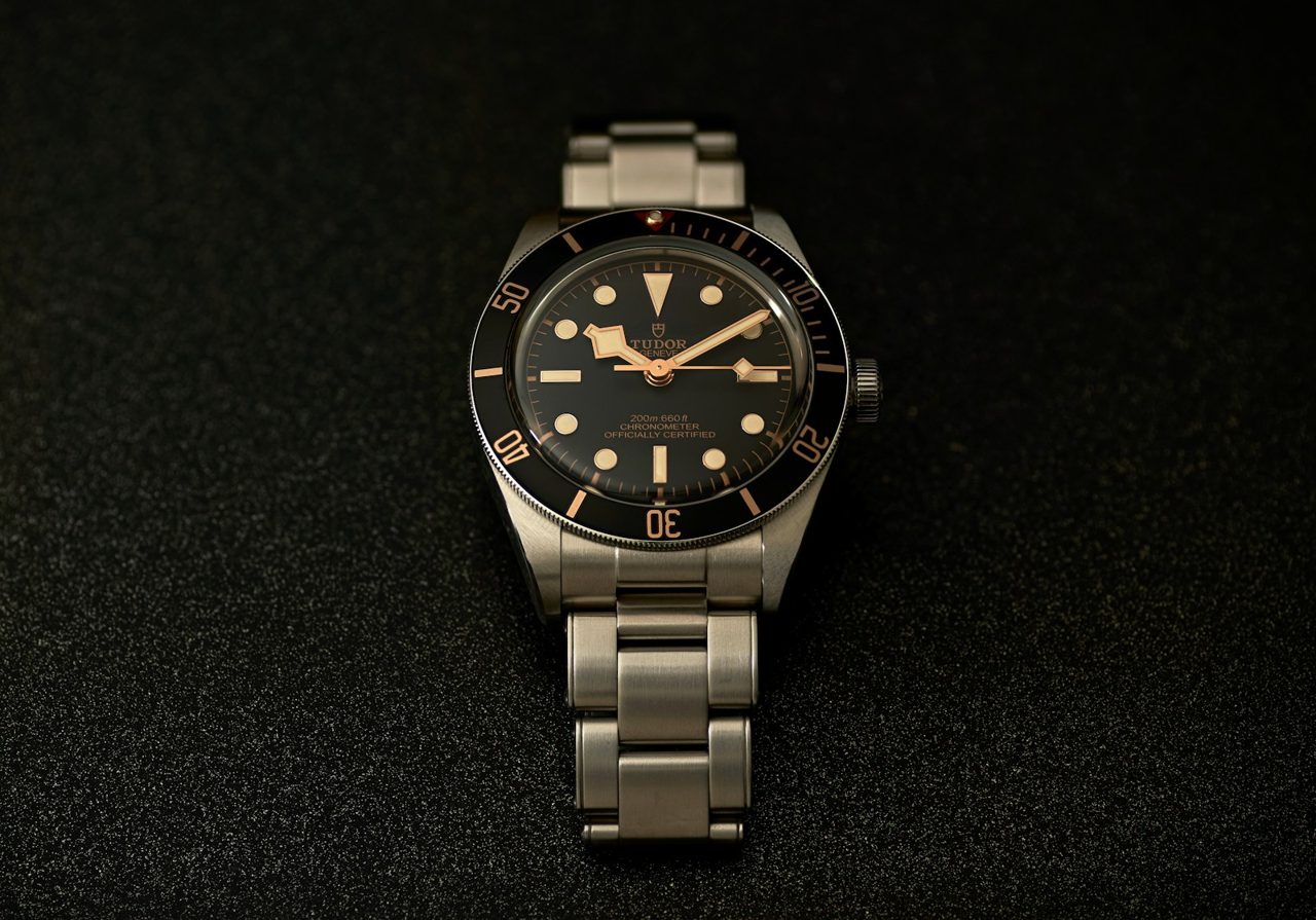 Tudor Black Bay Fifty-Eight mit schwarzem Zifferblatt, goldfarbenen Indexen und Stahlband auf schwarzem Stoff