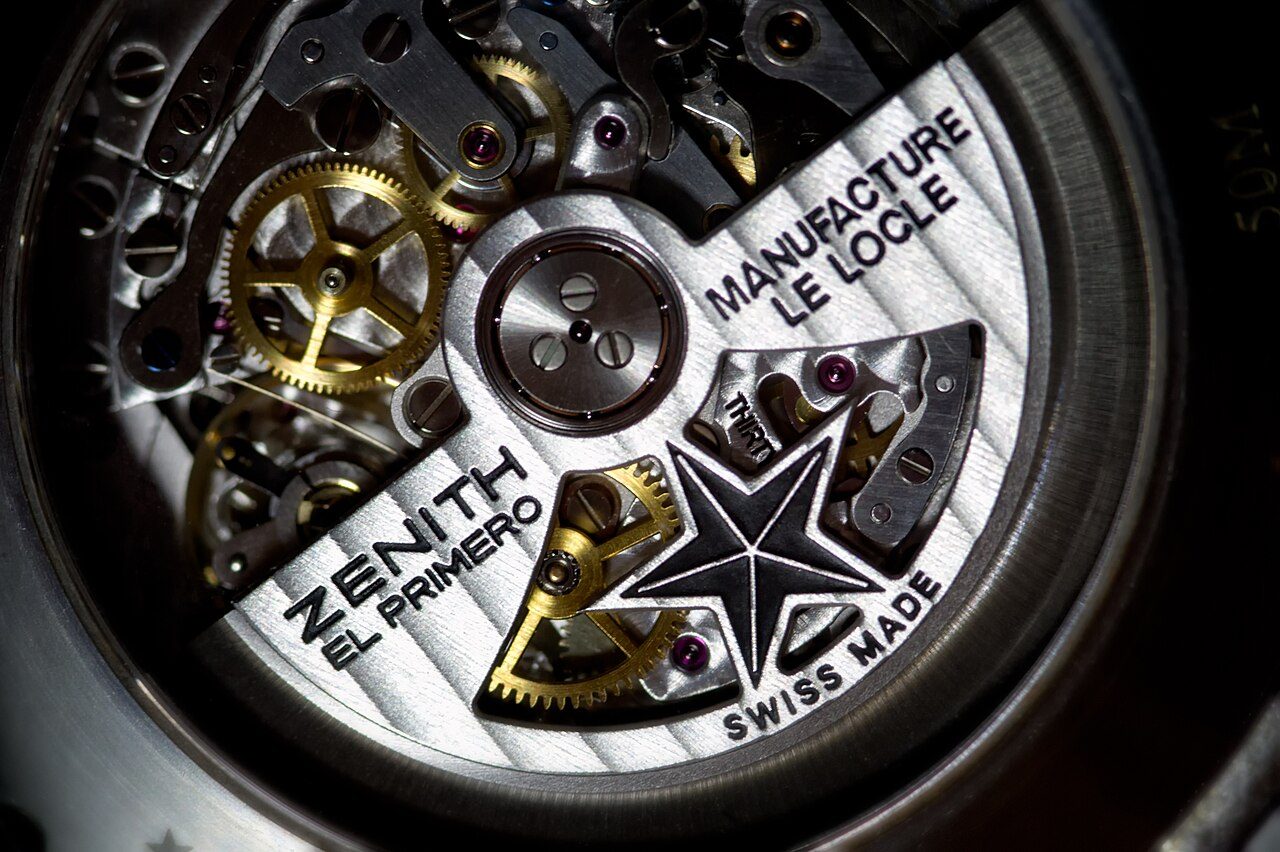 Nahaufnahme des Werks einer Zenith El Primero durch den Gehäuseboden, mit den Schriftzügen Manufacture Le Locle und Swiss Made sowie einem sternförmigen Rotor